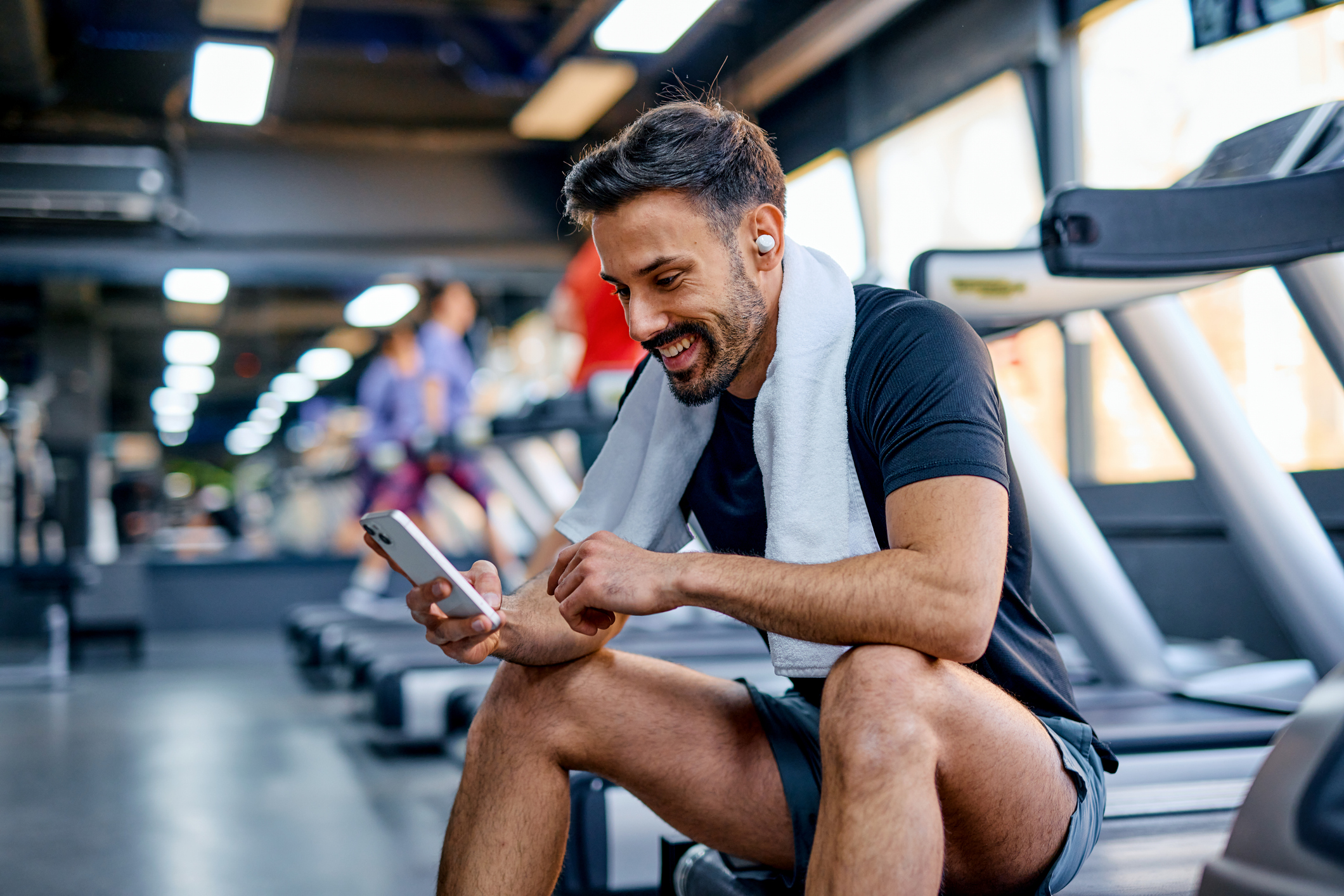 Smiling sportsman checking his phone after training in the gym