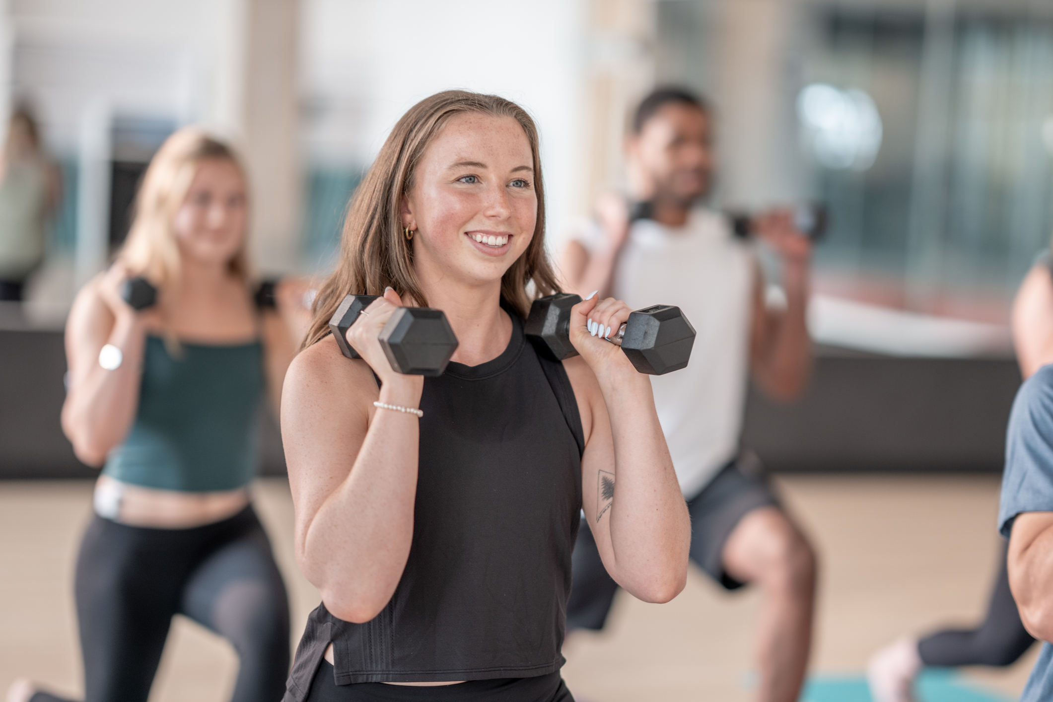 Group Strength Training Class with Participants Holding Dumbbells in a Gym Setting