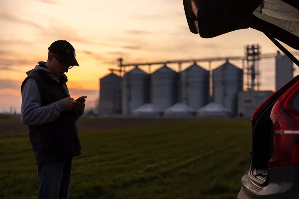 farmer in field with corn bins in the background