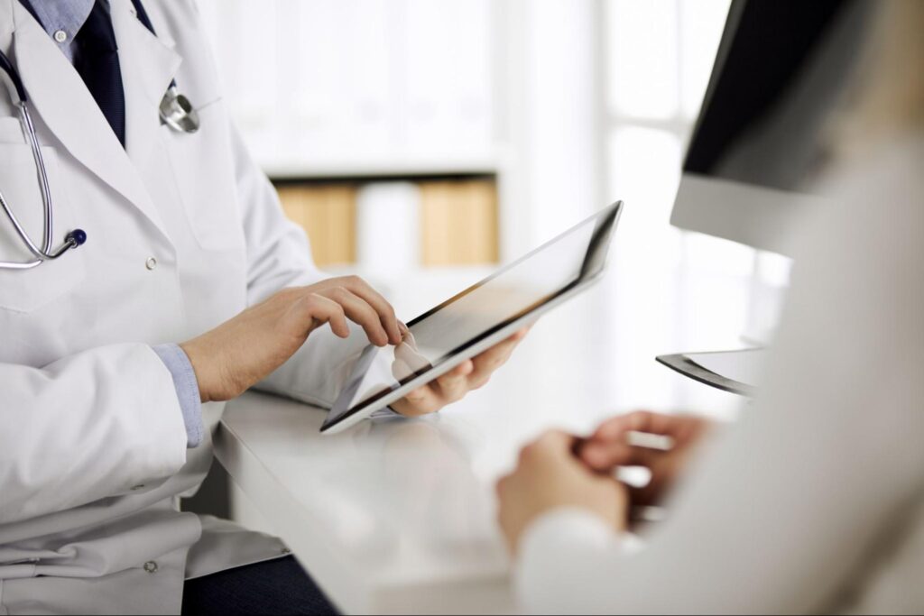 Healthcare professional reviewing patient data on a tablet during a digital health consultation, illustrating IoT in healthcare technology and connected medical devices